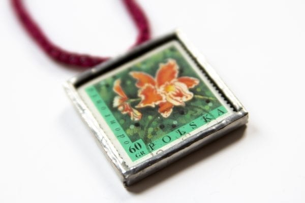 Dzikie Twory - naszyjnik ze znaczkiem pocztowym kwiat odontonia zbliżenie