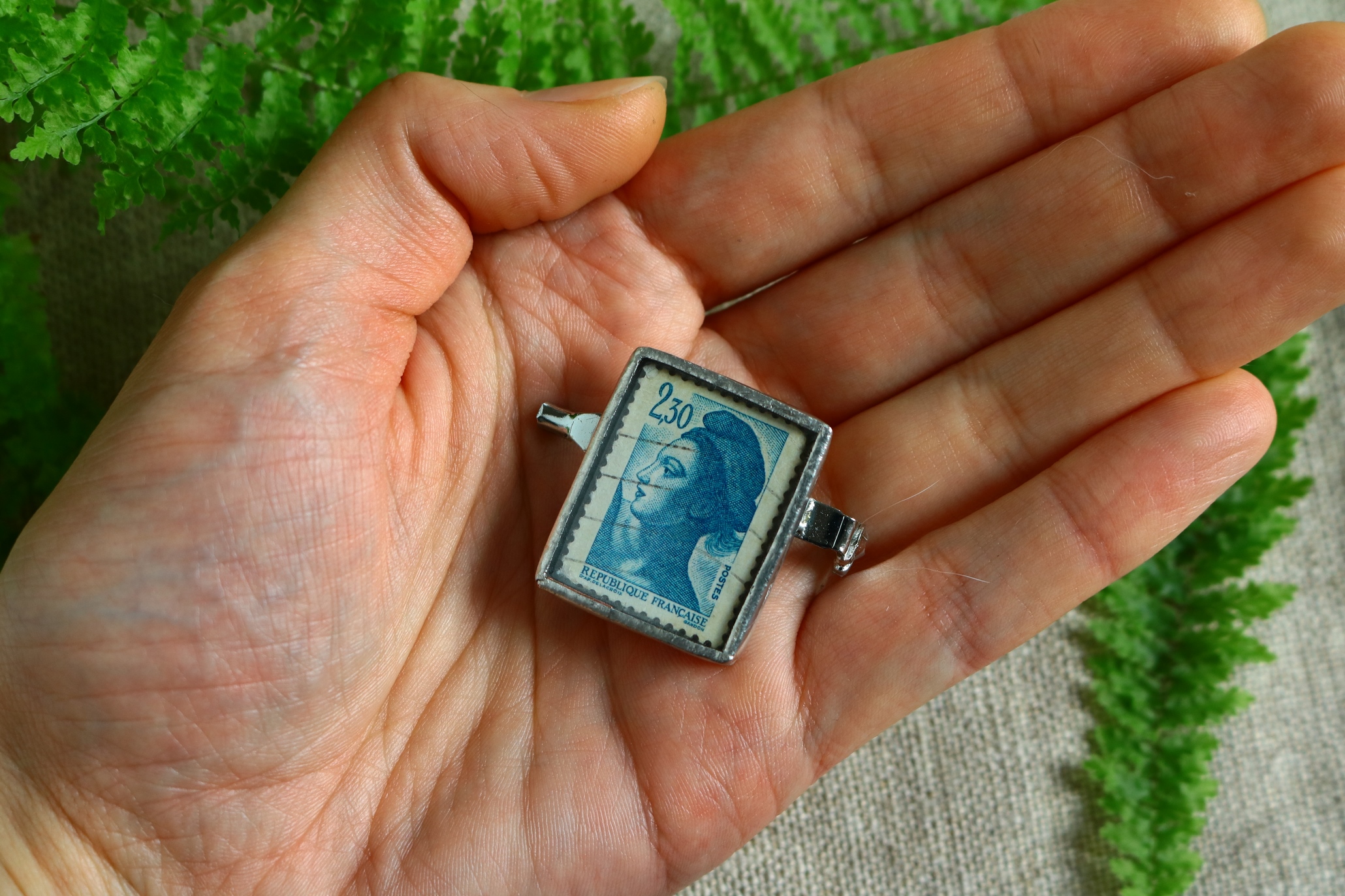 Dzikie Twory - broszka ze znaczkiem pocztowym z 1982 roku z Francji - postać kobieca alegoria wolności, wielkość broszki w skali dłoni