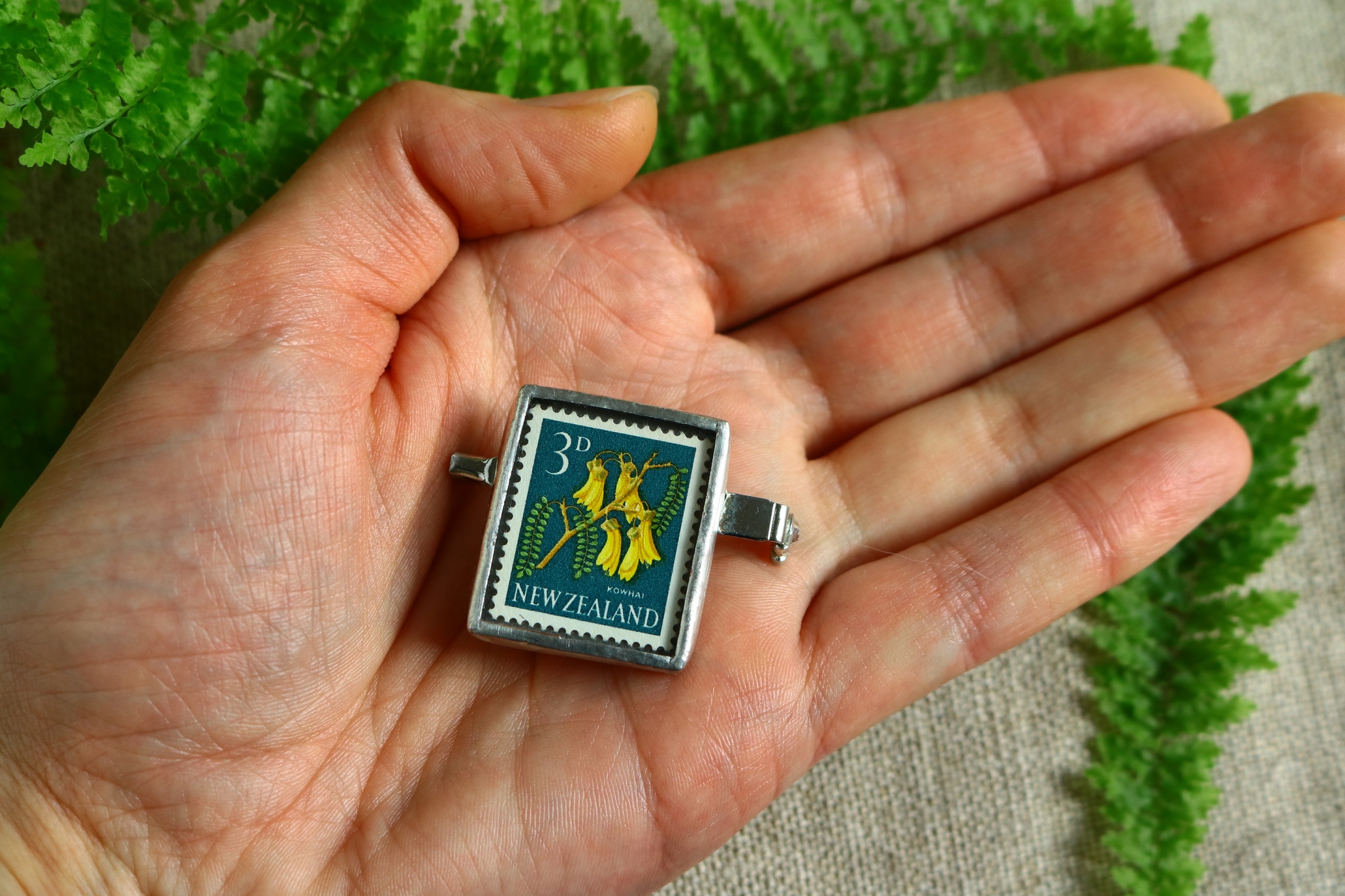Dzikie Twory - broszka ze znaczkiem pocztowym z ok. 1960 roku z Nowej Zelandii - roślina kowhai sophora, wielkość broszki w skali dłoni